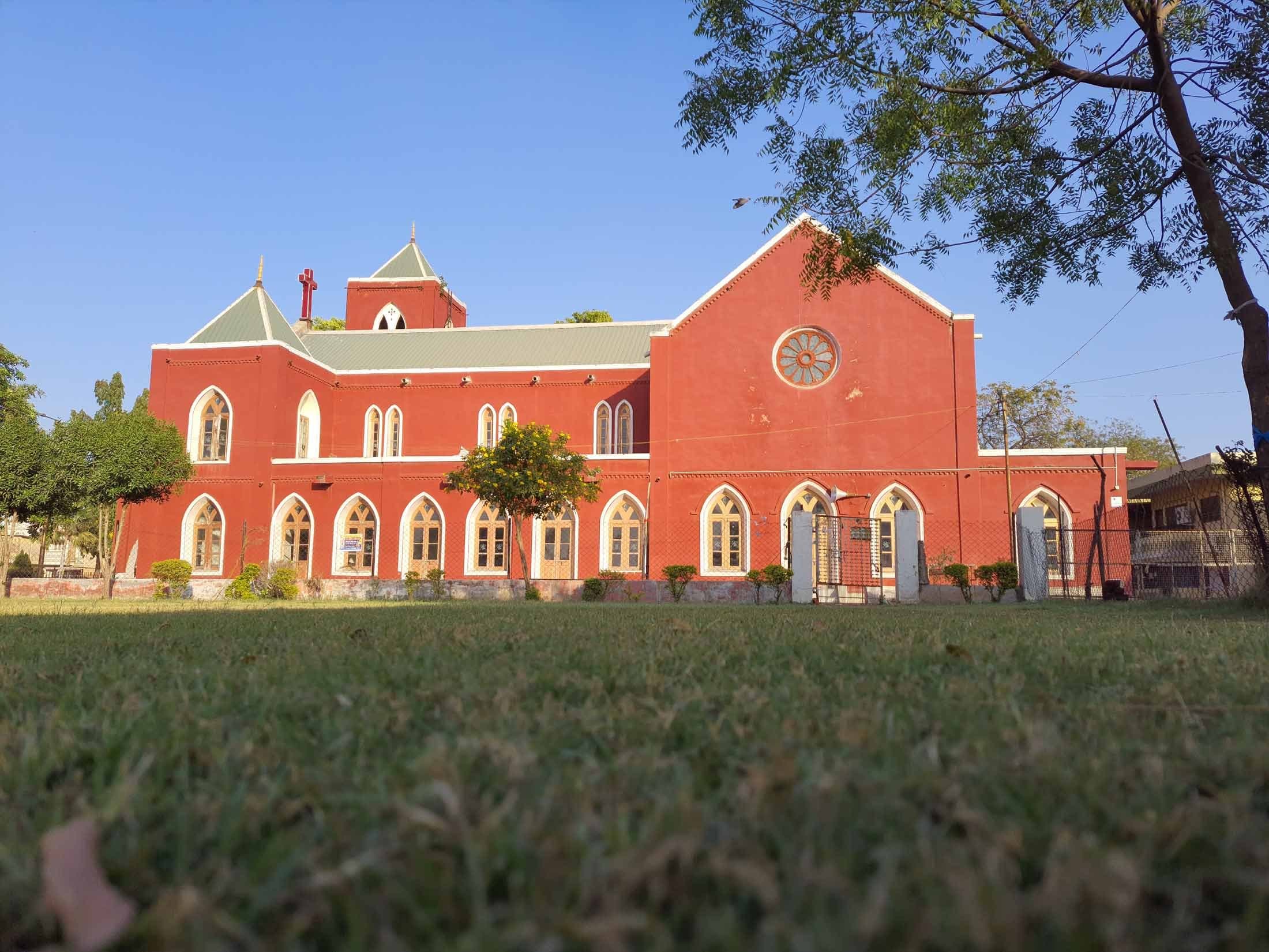 The church seen across the lawn, showing the gabled east end, the arcade of windows and the bell tower behind.