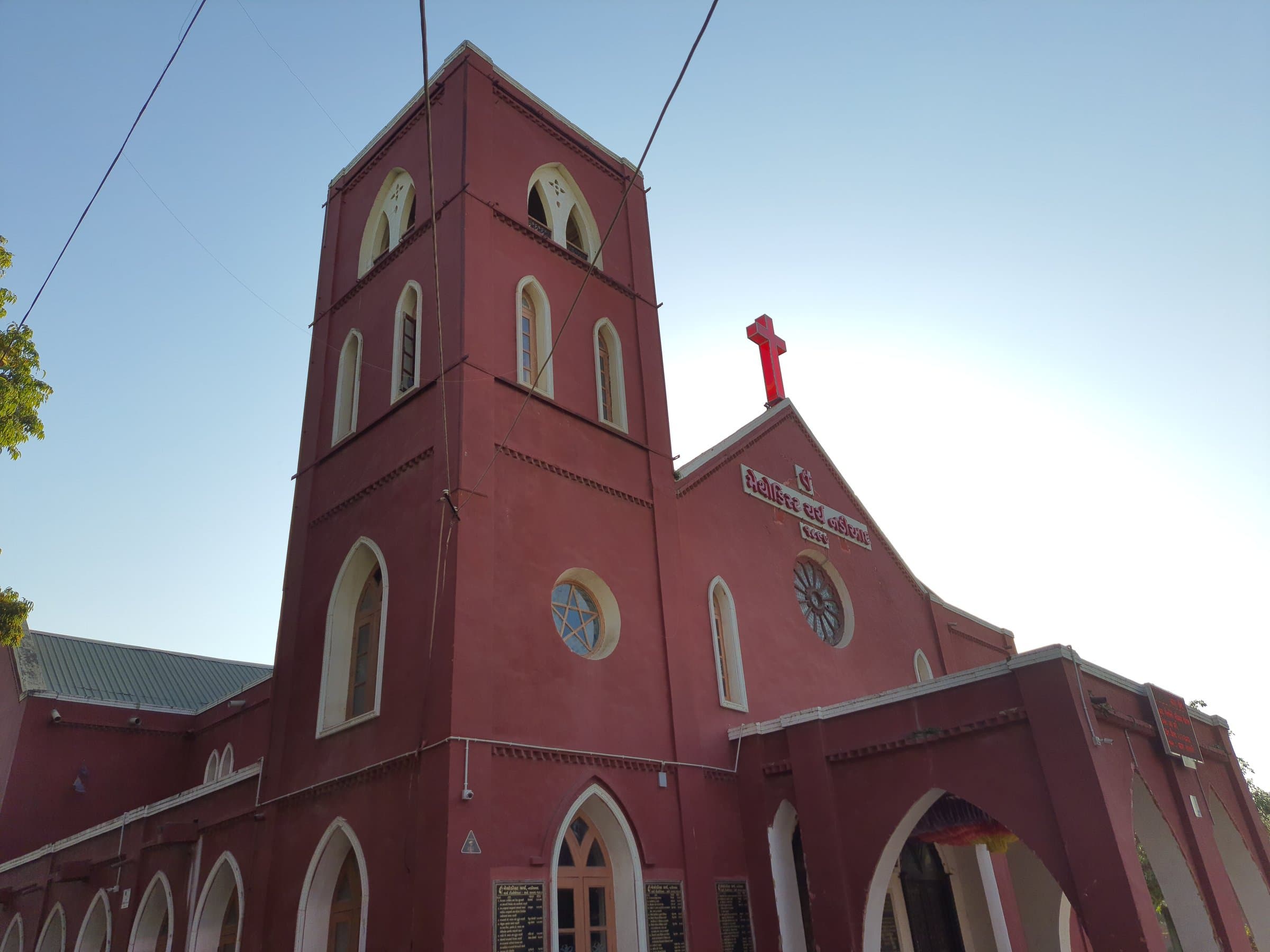 The bell tower of Methodist Church Nadiad from below, with the red cross, rose window and star window on the gable.
