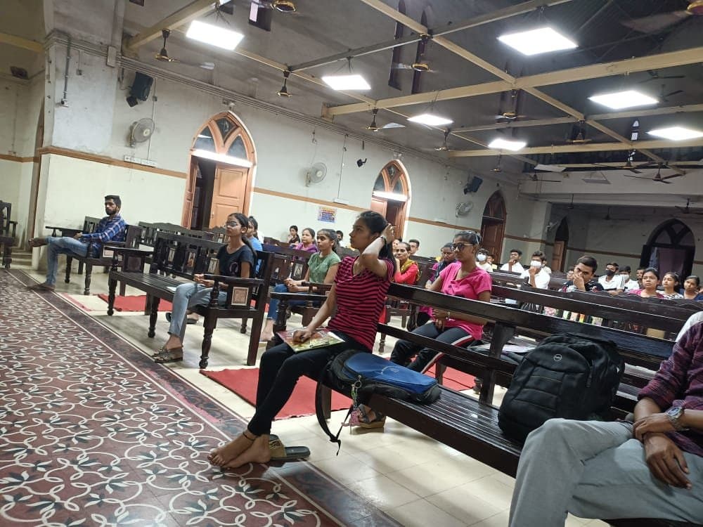 Members of the congregation seated on the wooden pews inside Methodist Church Nadiad during a gathering.