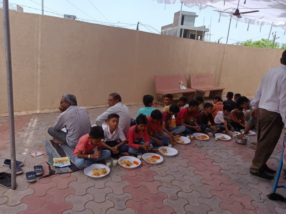 Children sitting together for a shared meal on the church terrace after a gathering.
