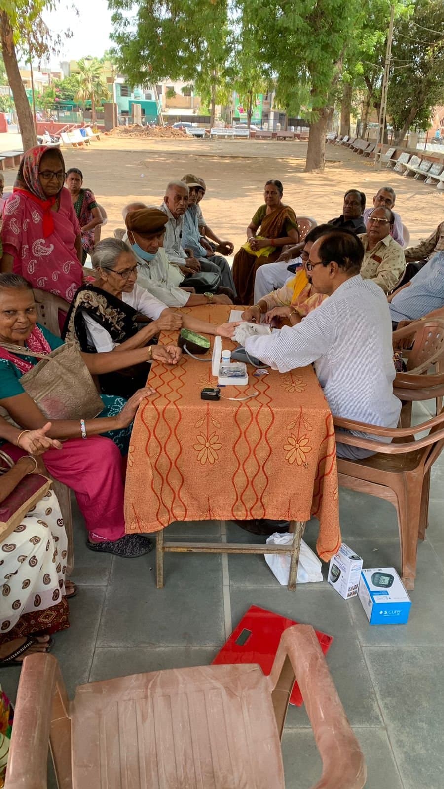 Older members of the community waiting their turn at the church health camp as a doctor takes blood pressure readings.